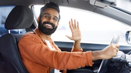 cheerful-indian-man-gesturing-hi-from-driver-s-sea-2023-11-27-05-31-58-utc